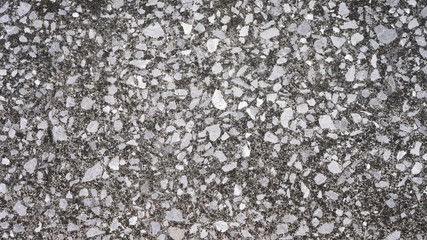 Small gray stones laid on the path. Light gray asphalt road background. Stone texture. Many old stones on the passer