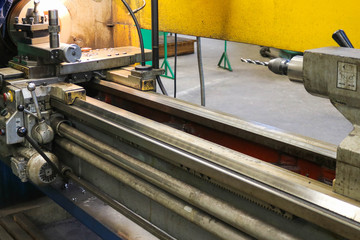 A large powerful iron metal bench-type screw-cutting lathe for the manufacture of parts and spare parts with handles and buttons, vise drills and clamps at an industrial plant