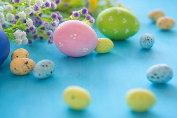 Colorful easter eggs with flowers on blue wooden table