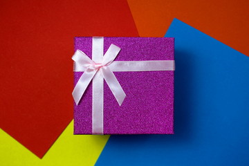 Bright gift box with a bow on a background of bright different tones