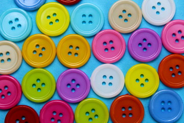 Texture of multi-colored buttons laid out on a blue surface