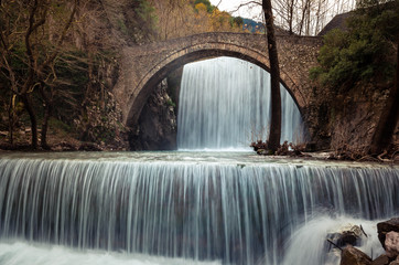The historical stone arched bridge of Palaiokarya with its two artificial waterfalls,  creates a magnificent, inspiring image.