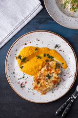 Baked chicken under cheese with carrot puree on a plate. Top view