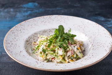 Tasty salad with crab sticks on a plate.