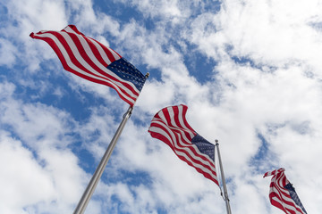 US flags, national symbol of USA waving against blue sky in New York city