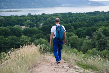 Naklejka na ściany i meble elderly man with backpack on the mountain. Senior man walking in nature. travel tourism concept. Outdoor activities on weekends.