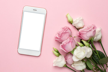 Mobile phone with pink and white roses flowers on pastel background.Minimalistic composition for the holidays,valentines day and womens day.