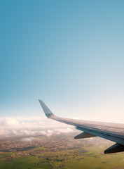 aiplane window view with ariplane wing, landscape and blue sky copy space -