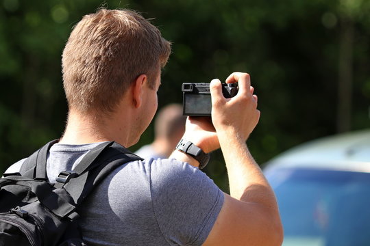 Young man with photo camera take video