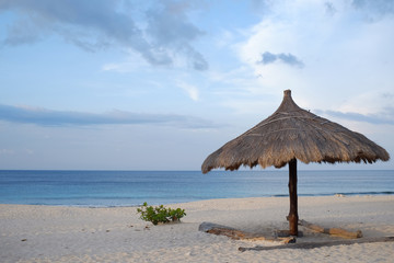 Umbrellas from thatch, calm blue sea and white sand on the Kita beach Mananga Aba, Southwest Sumba, Indonesia