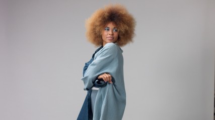 portrait in studio mixed race black woman in denim oversized shirt and huge afro hair