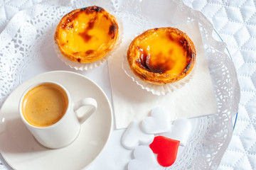 portuguese dessert egg tart. pastel de nata. breakfast in bed with love. sweet pastry and small cup of coffee. red hearts on a plate.