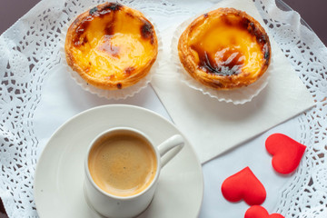 portuguese dessert egg tart. pastel de nata. breakfast in bed with love. sweet pastry and small cup of coffee. red hearts on a plate.