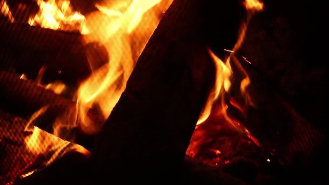 Flames and embers burning brightly in a wood fire at night