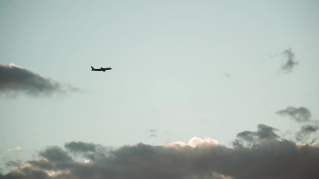 Silhouette airplane flying up in the sky during the sunset
