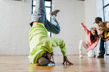 selective focus of african american dancer breakdancing near emotional man and woman