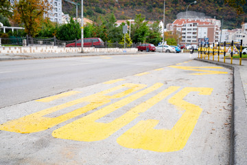 The special place for bus stop with yellow inscription on asphalt. City view background, outdoors.