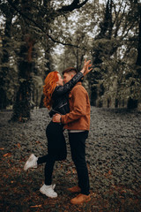 Fototapeta premium Romantic vacation of a guy and a girl in the autumn park. Fun games of a young couple in nature.