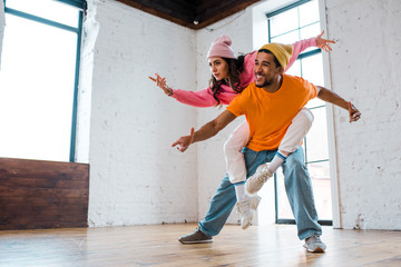 cheerful african american man piggybacking attractive dancer