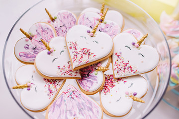 Gingerbread cookies covered with multi colored icing in pale pastel colors shaped as heart unicorn.Birthday cakes