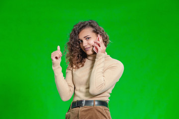 Coquettish young female flirting with her boyfriend on phone, playing with lock of her hair, looking ridiculously funny.