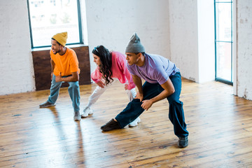young woman and stylish multicultural men in dance studio