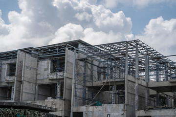Fototapeta na wymiar Building and Construction Site in progress. Building construction site against cloudy sky. Metal construction of unfinished building on construction of multi storage building.