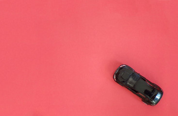 Red background with a black toy car.