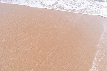 White wave bubbles on red sand beach in the evening