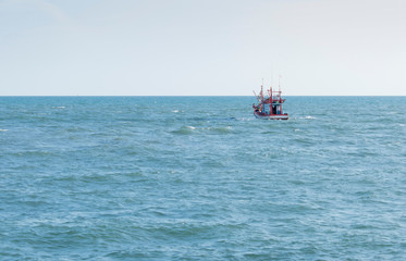 Small red and white fishing boat Sailing out into the sea to find fish In the midst of a strong wind In the evening of the day