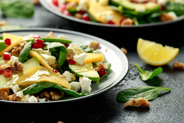 Persimmon, avocado salad with spinach, feta cheese, walnuts and pomegranate seeds. Healthy food.