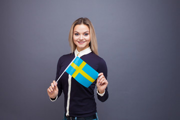 Immigration and the study of foreign languages, concept. A young smiling woman with a Sweden flag...