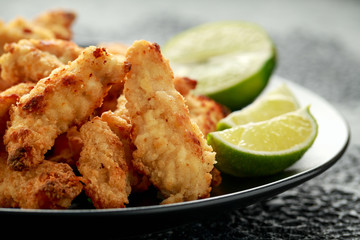 Buttermilk chicken nuggets served on black plate with lime wedges