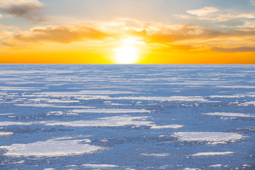 frozen river in a snow at the sunset, dramatic evening winter background