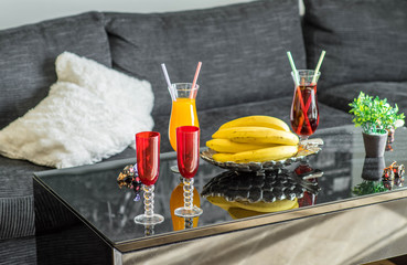 Bananas and orange on the plate. Couple of drinks. Red wine glasses. Close-up.