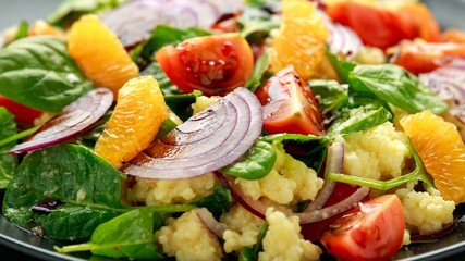 Vegetable Millet salad with red onion, cherry tomatoes, spinach, tangerine and clementine dressing. healthy food