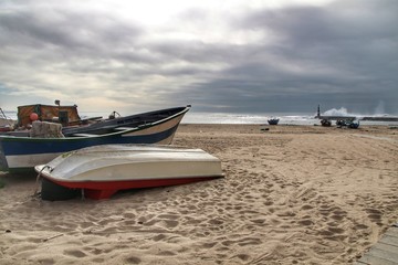 Naklejka premium Fishing boats stranded on Aguda beach and Giant waves breaking on the breakwater