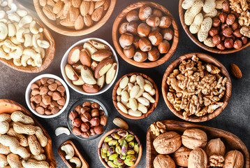 Mixed nuts in wooden bowls on black stone table. Almonds, pistachio, walnuts, cashew, hazelnut. Top view nut photo.