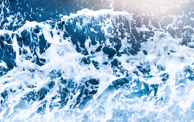 Aerial view of salt ocean foam and waves. Blue water aqua sea background ot texture. Rippled spashing wave.