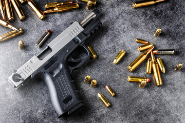 Gun with ammunition on dark stone background. Ammo projectiles or rounds military concept.