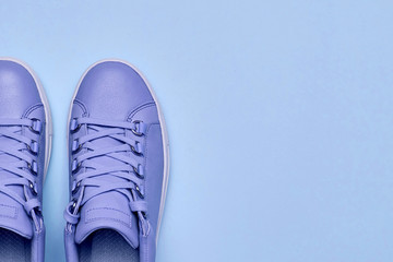 Stylish violet female shoes on blue pastel background, copy space. New sneakers. Beauty and fashion concept. Flat lay, top view. Overhead shot