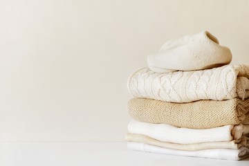 A stack of warm beige knit sweaters. The concept of capsule wardrobe, comfort. Close-up with copy space for text.