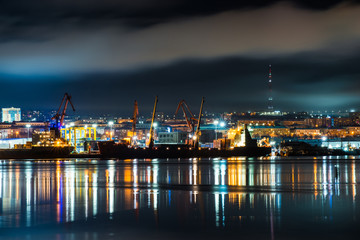 Fototapeta na wymiar night Murmansk, city lights reflected in the Bay and the ships standing in the port