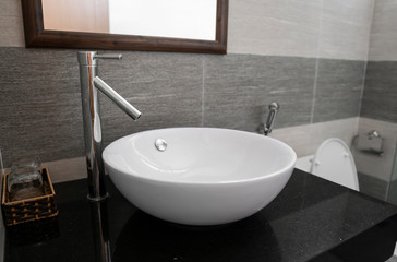 Bathroom interior with white round sink and chrome faucet in a modern bathroom.