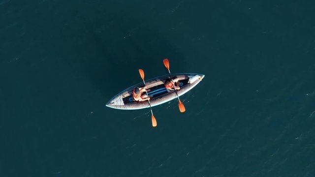 Aerial view drone happy mother and son rowing in inflatable kayak on water of large lake with dog on background of picturesque cliffs, green vegetation, beautiful sunset day. Family sport. Lifestyle