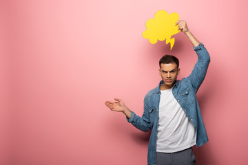 Angry man with speech bubble pointing with hand and looking at camera on pink background