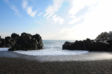 Waves rushing into the beach between the rocks.