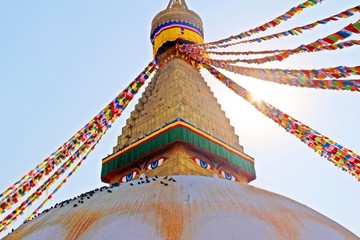 One side of Boudha Stupa / Sun bright through the flags at Boudhanath stupa, one of the largest spherical stupas in in Kathmandu, Nepal