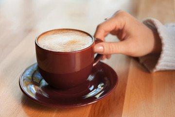 Woman with aromatic coffee at table in cafe, closeup