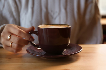 Woman with aromatic coffee at table in cafe, closeup